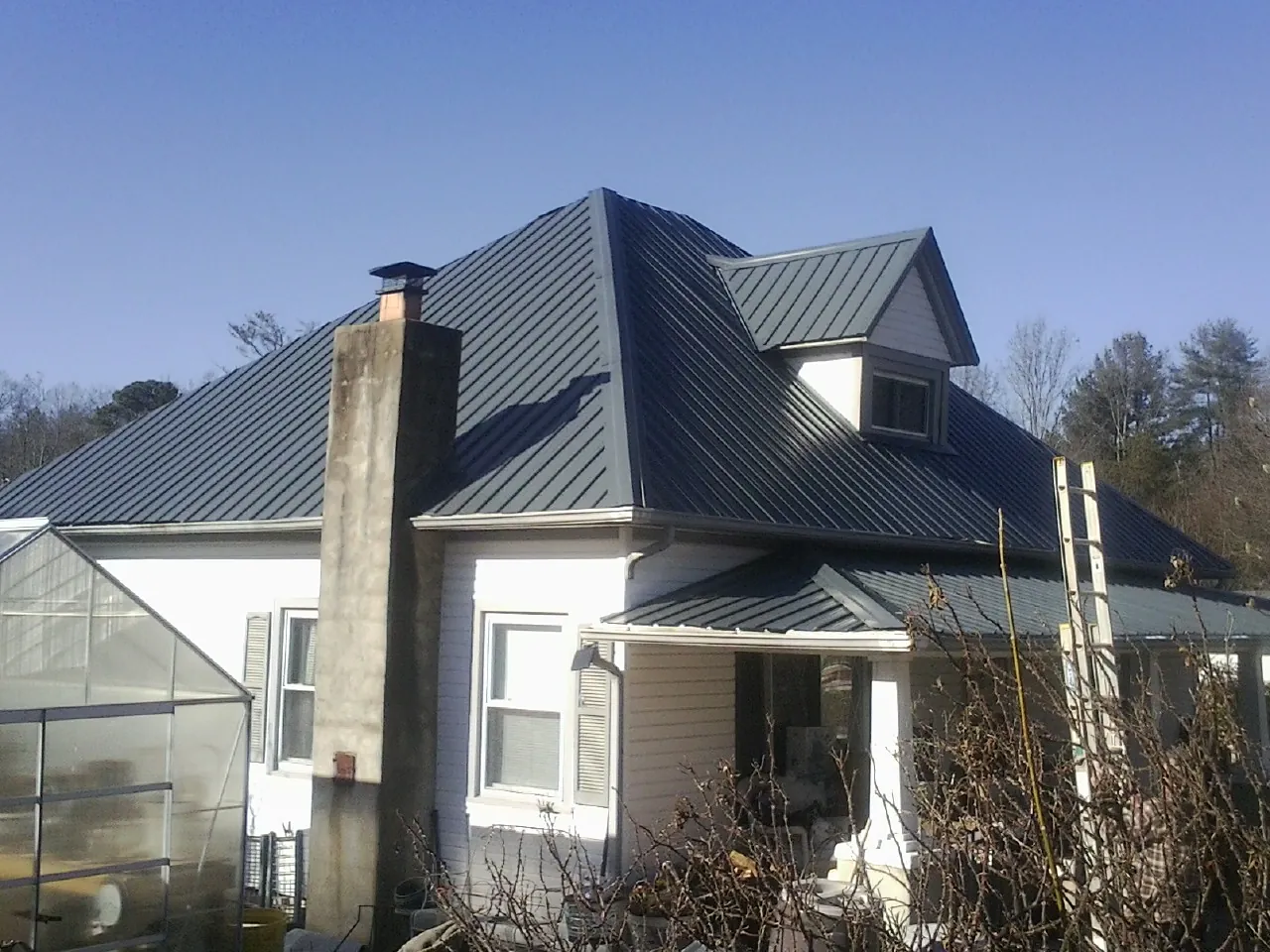 Dark blue standing seam metal roof on a white farmhouse with dormer — Slate & Tile Roof Repair by Roofing Brothers in Ramsey