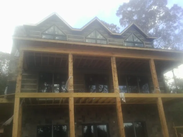 Dormers and porch framing on a large log home under construction — Roof Coating work by our crew in Ramsey