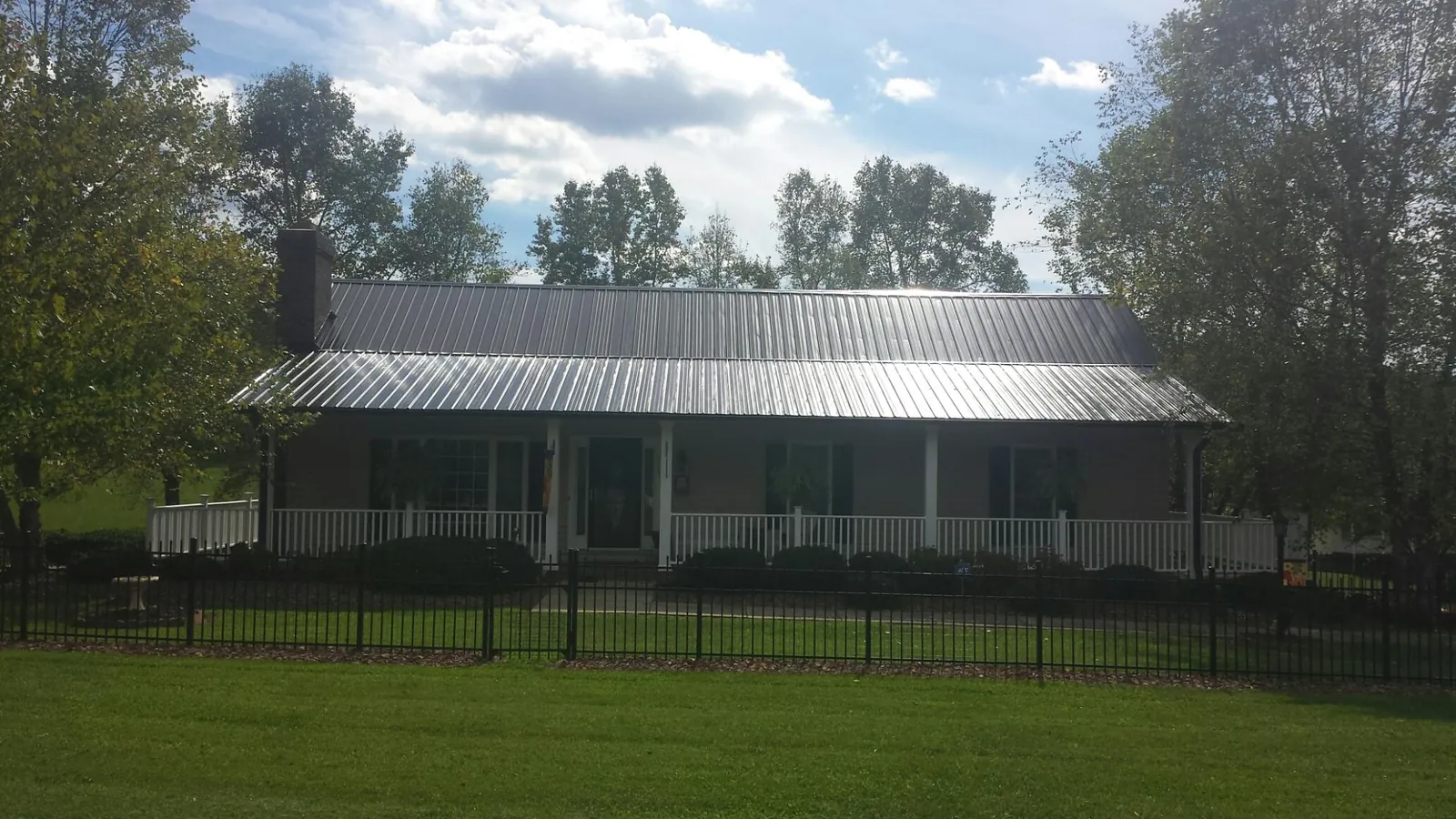 Gray metal roof on a brick ranch with a full width front porch — Gutter Guard Installation work by our crew in Ramsey