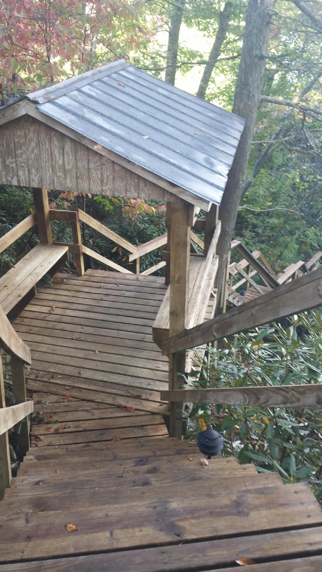 Metal roofed shelter over wooden steps on a wooded walkway — Skylight Repair & Installation work by our crew in Ramsey