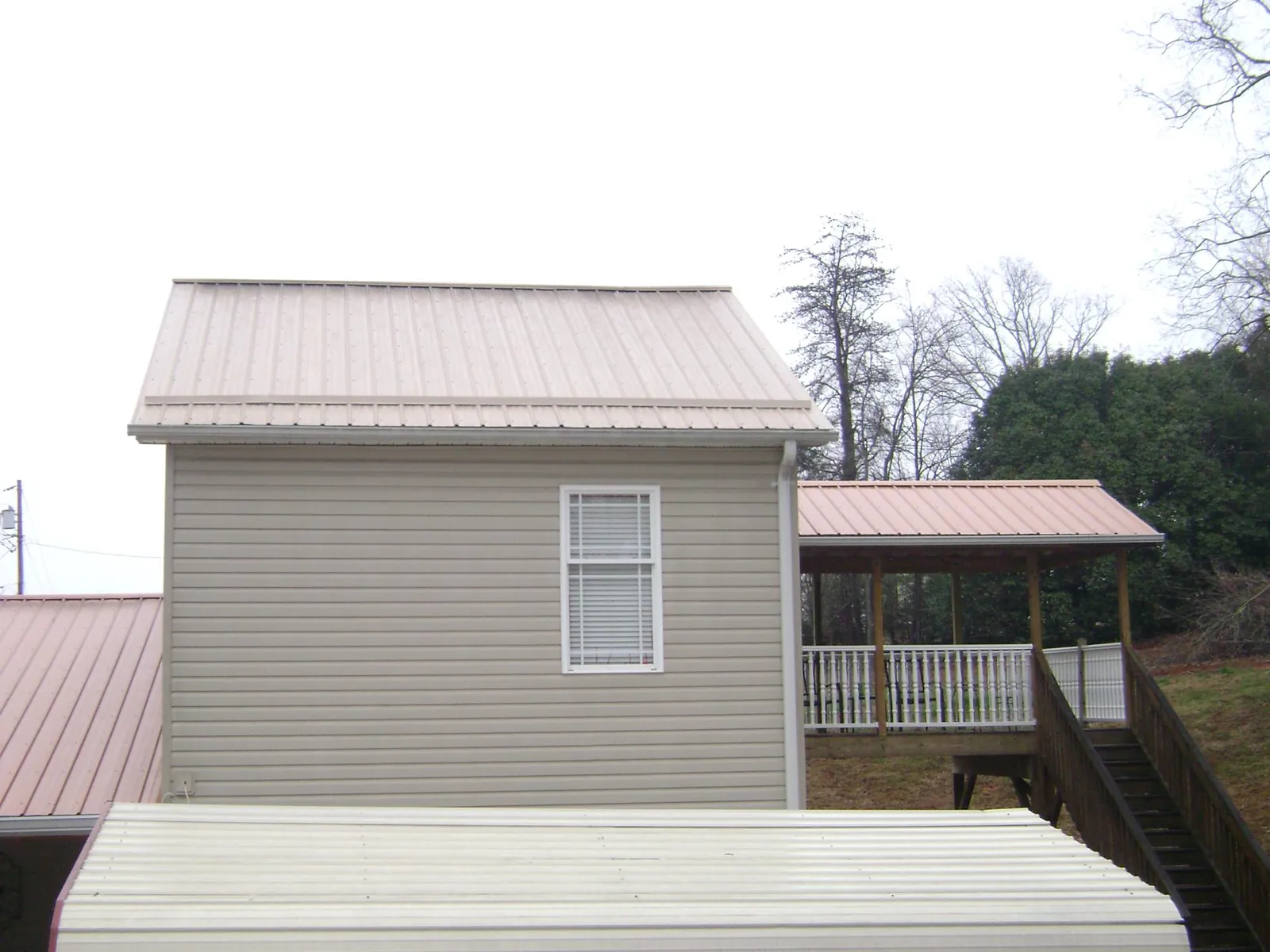 Tan metal roofs on a two story addition and attached porch, from a Roof Replacement job in Ramsey