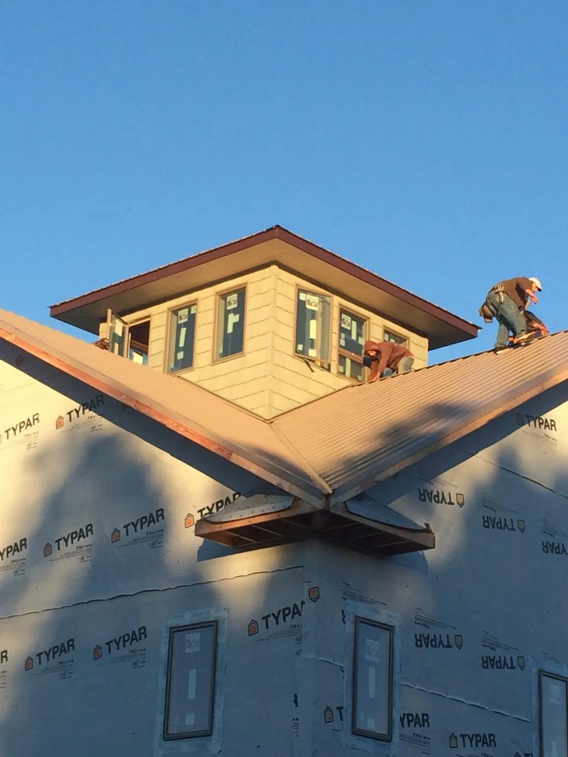 Roofers working around a rooftop cupola on a new metal roof at sunset — Roof Waterproofing in Ramsey by Roofing Brothers